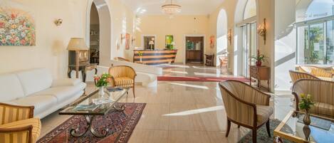 A spacious lobby with a reception desk, seating area, and a chandelier.