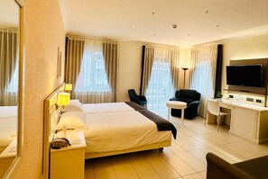 Une chambre d’hôtel avec un grand lit, un bureau, une chaise et un téléviseur.