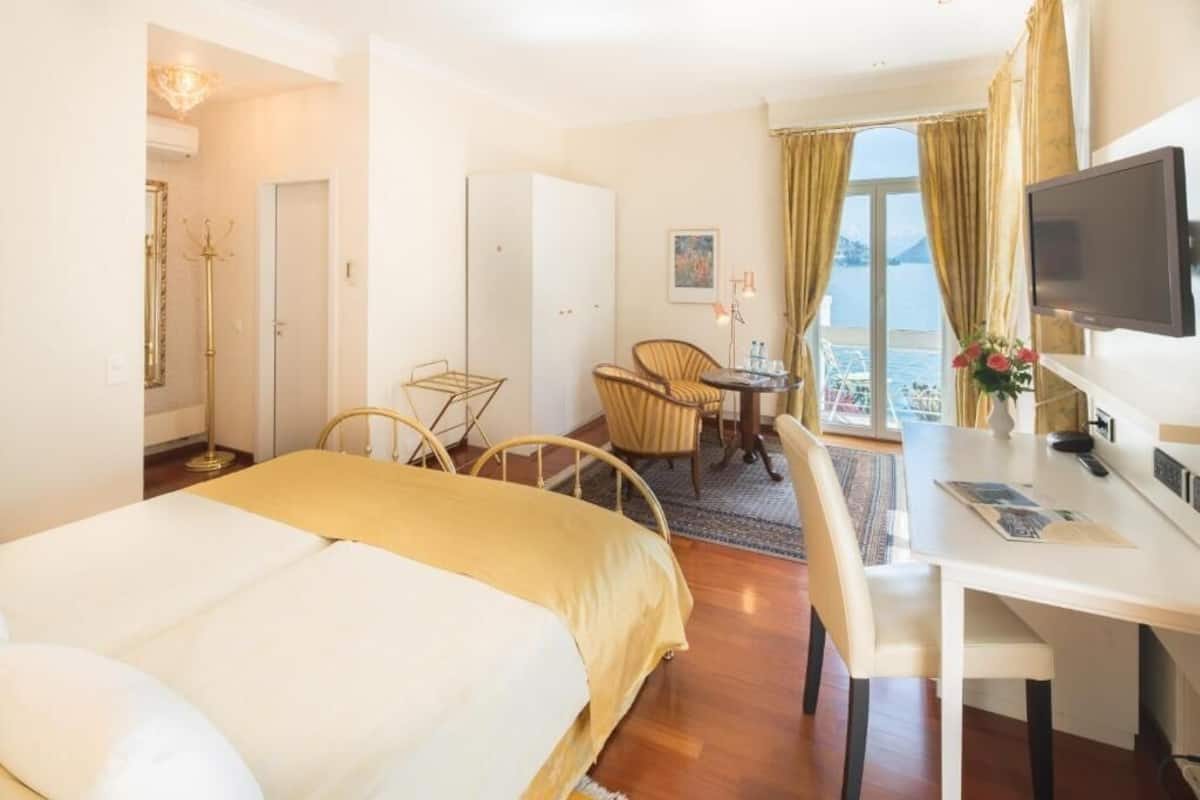 Habitación de hotel con cama, escritorio, silla, televisor y vista al mar.