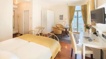 Una camera d'albergo con un letto, una scrivania, una sedia, una TV e vista sul mare.