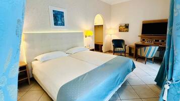 A hotel room with a large bed, a desk with a chair, a television, and a painting on the wall.