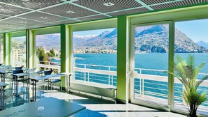 Un espacio interior moderno con ventanas amplias que ofrecen vistas a un lago y montañas.