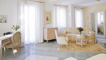 A spacious room with a large bed, a desk, and a sofa. There is a window with curtains and a painting on the wall.
