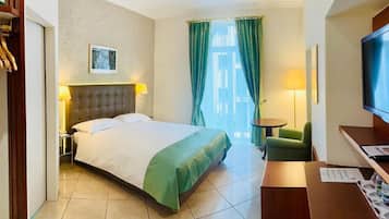 Ein Hotelzimmer mit einem Bett, einem Schreibtisch, einem Sessel, einem Fernseher und einem Fenster mit Vorhängen.