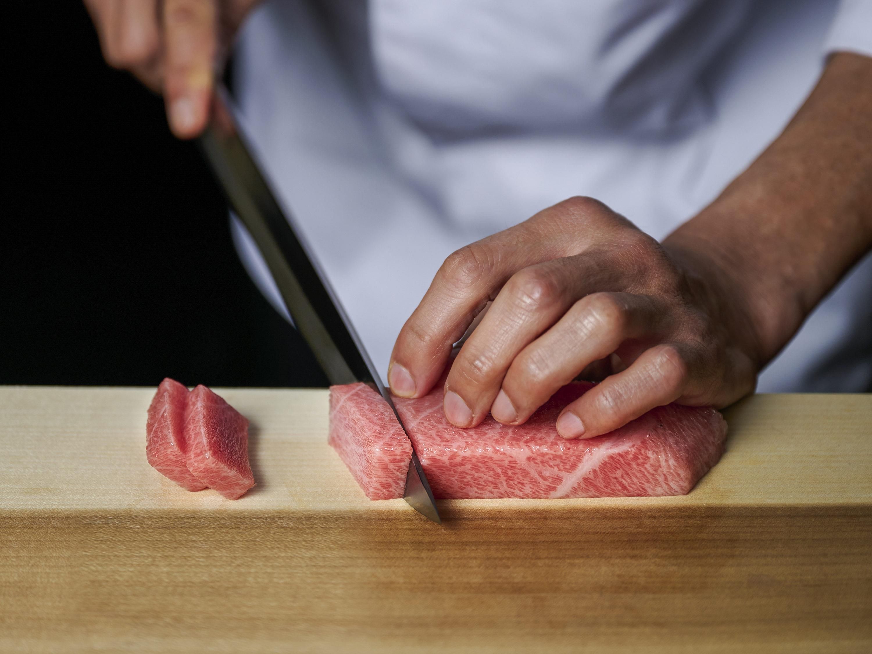 Una persona cortando carne sobre una tabla de madera.