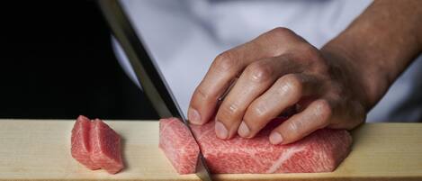 A person cutting meat on a wooden board.