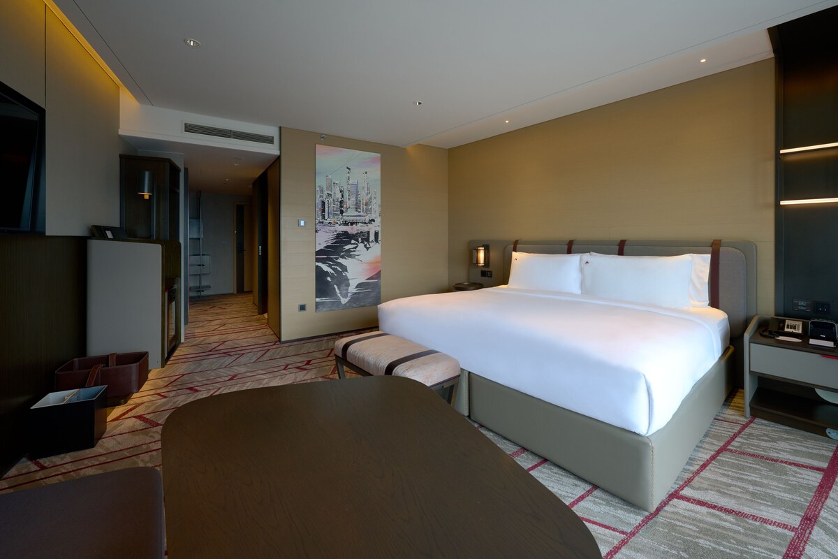Een moderne hotelkamer met een groot bed, een bureau en een zithoek.