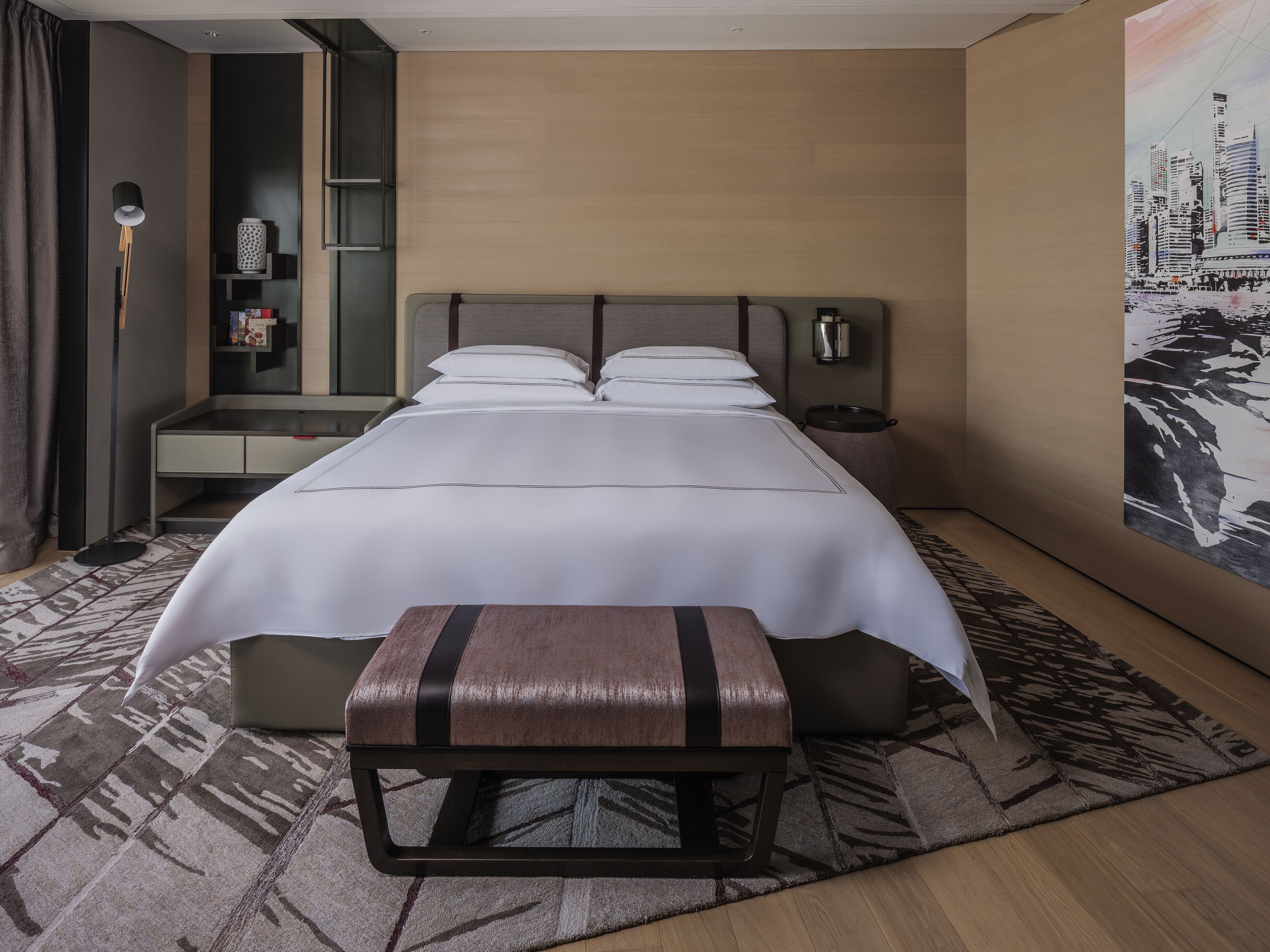 Ein Hotelzimmer mit einem großen Bett, einem Nachttisch, einer Lampe, einem Bücherregal und einem Gemälde an der Wand.