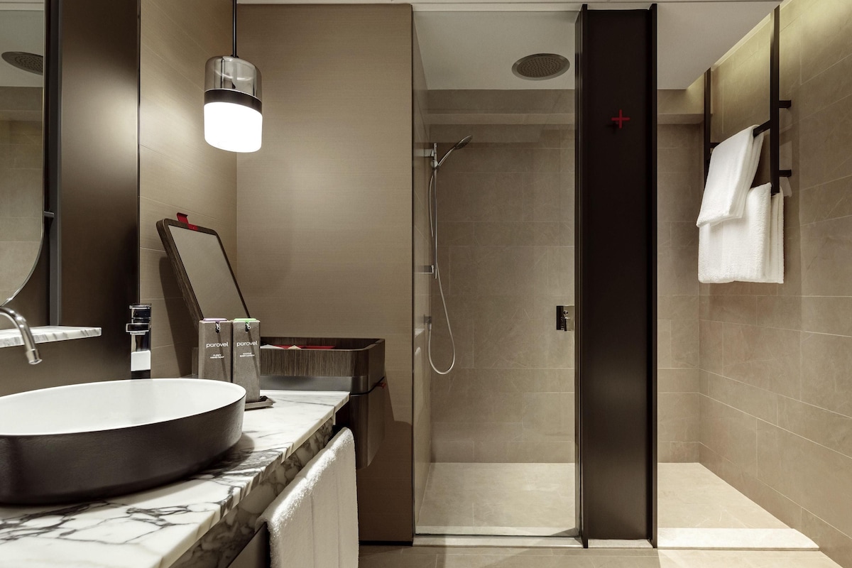Une salle de bain moderne avec un lavabo rond, un miroir, un espace douche et un porte-serviettes.