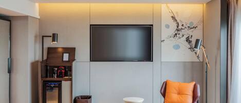 Una sala de estar moderna con televisor de pantalla plana, cafetera, una mesita y un sofá con cojín.
