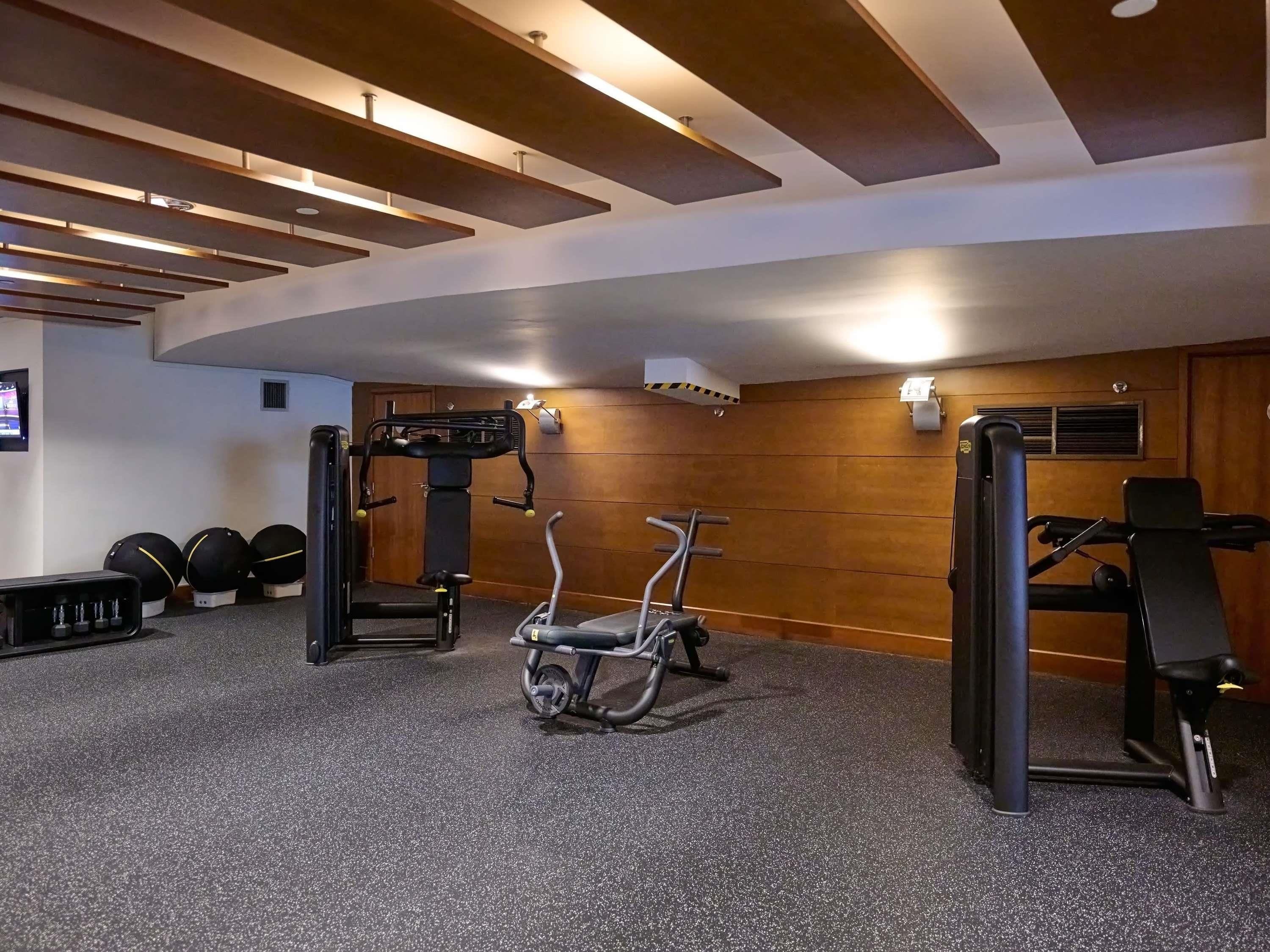 A gym with exercise equipment, a wall-mounted TV, and a wooden wall.