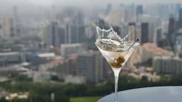 Un verre à martini contenant un peu de liquide, posé sur une table, avec une vue sur la ville en arrière-plan.