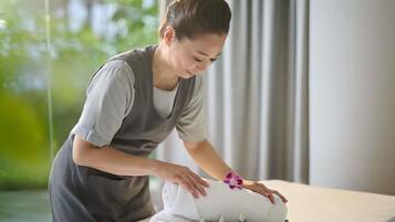 A person attending to a massage table with towels and massage tools.