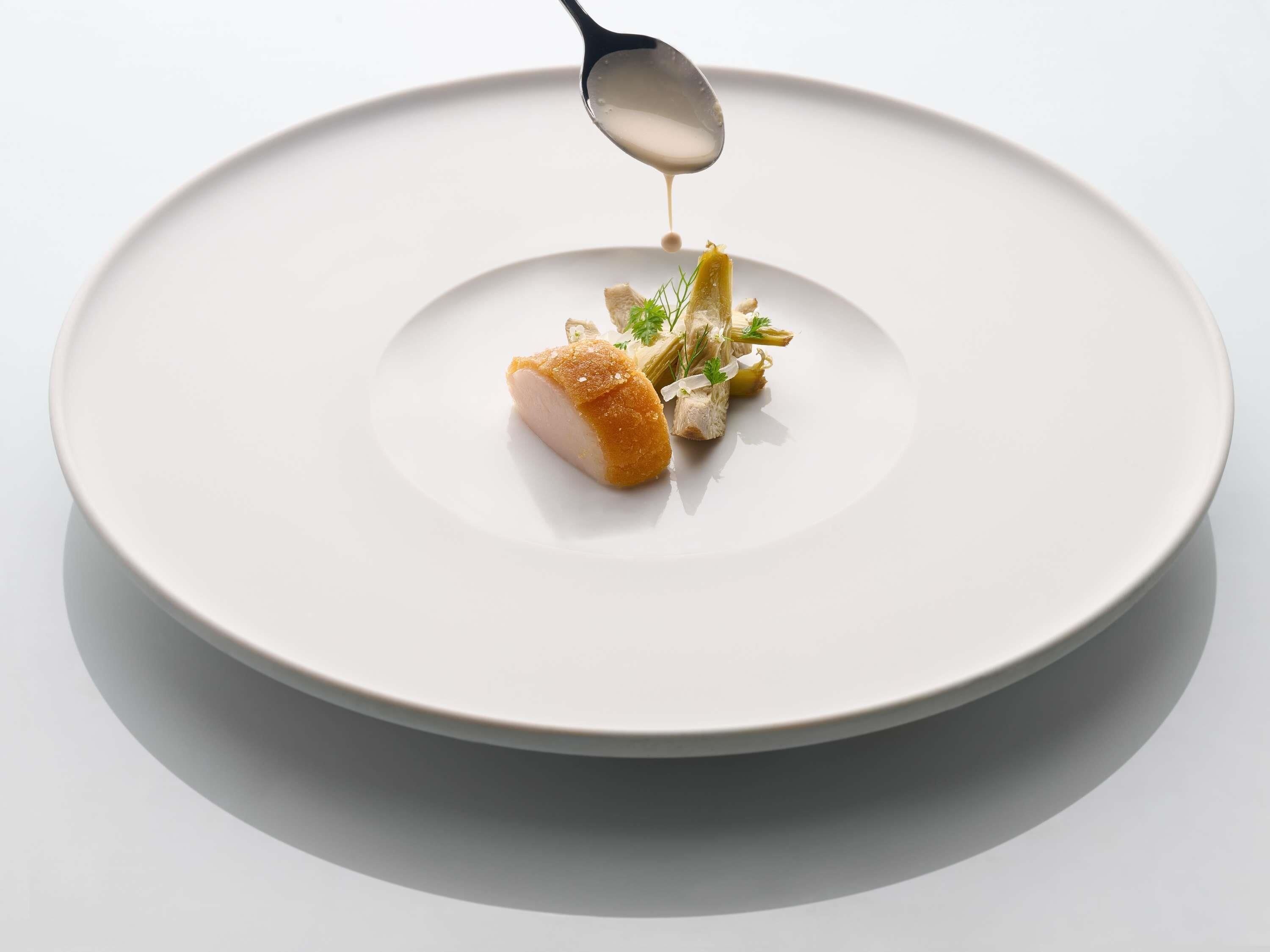 Ein weißer Teller mit einer Portion Essen und einem Löffel.
