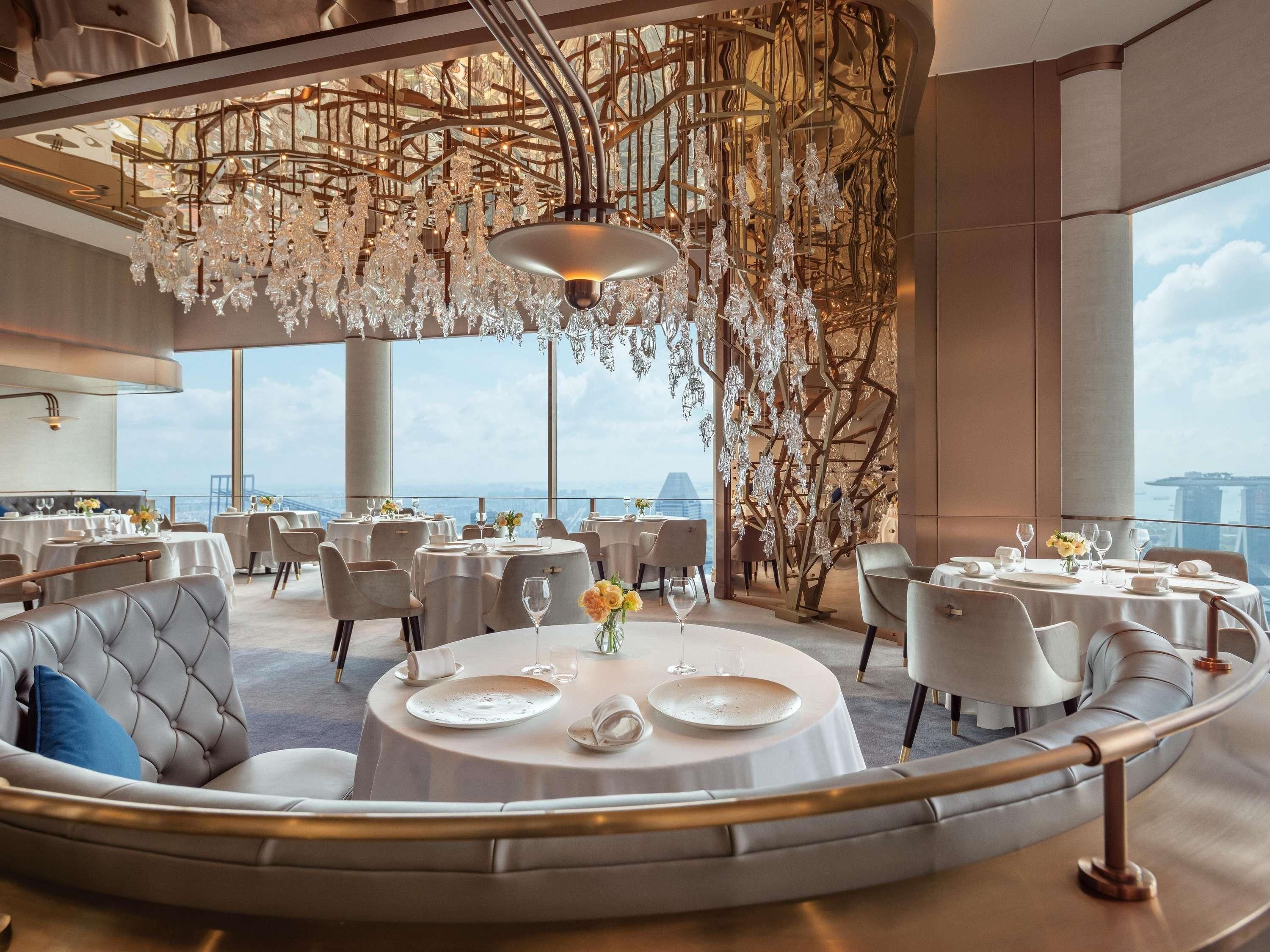 A modern dining area with round tables, elegant chairs, and a view of the cityscape.