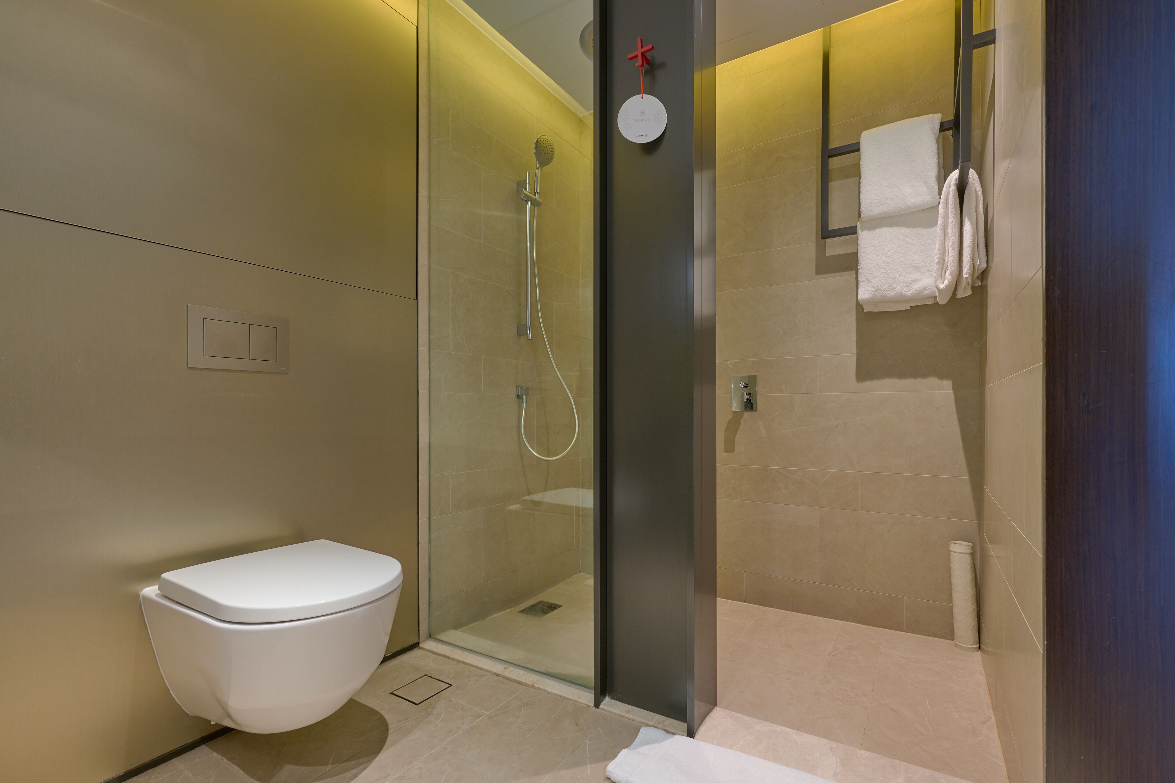 A modern bathroom with a glass-enclosed shower, a toilet, and a towel rack.