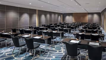A conference room with rows of tables and chairs, equipped with nameplates and water glasses.