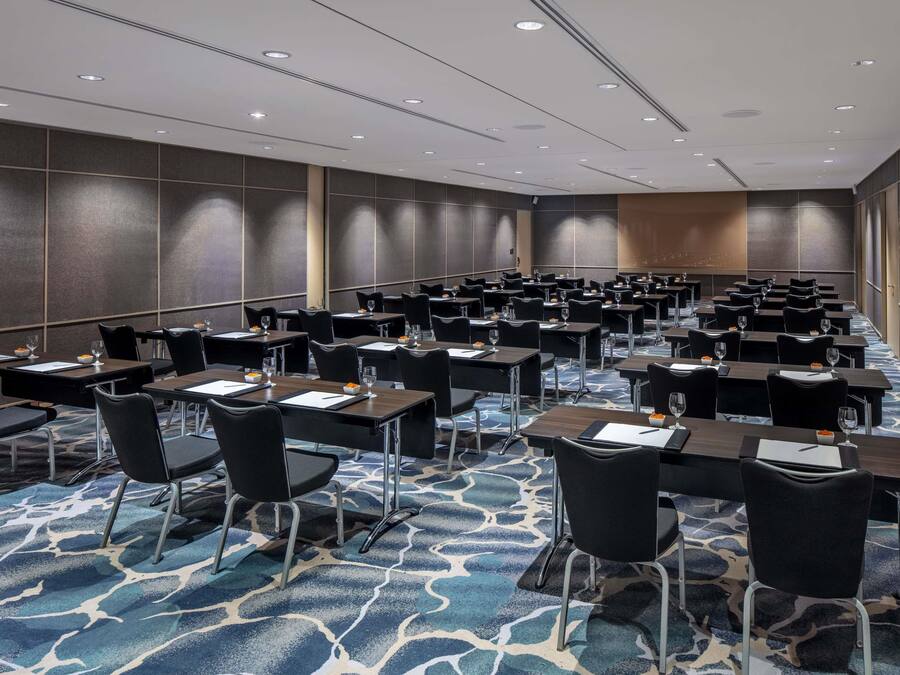 A conference room with rows of tables and chairs, equipped with nameplates and water glasses.