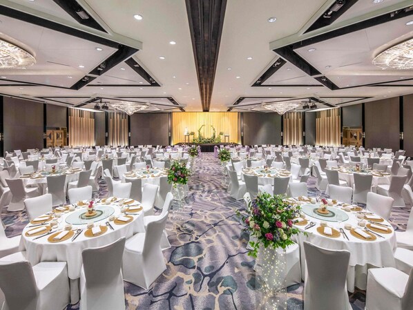 A large banquet hall with round tables, white chairs, and floral centerpieces. - Swissotel The Stamford, Singapore (Singapore)