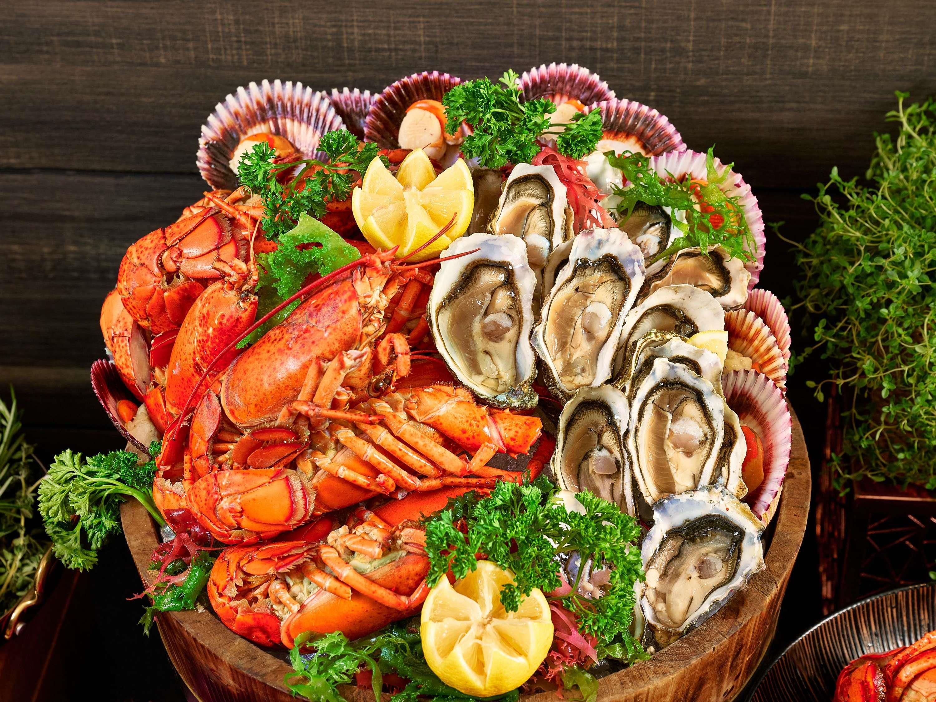 A wooden bowl filled with seafood, including lobsters, oysters, and garnishes.