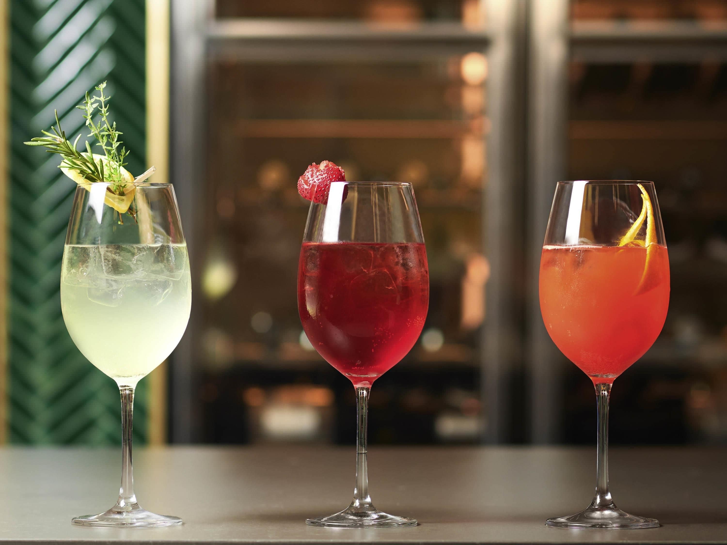 Drie cocktails met garnering op een bar.
