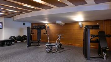 A gym with exercise equipment, a wall-mounted TV, and a wooden wall.