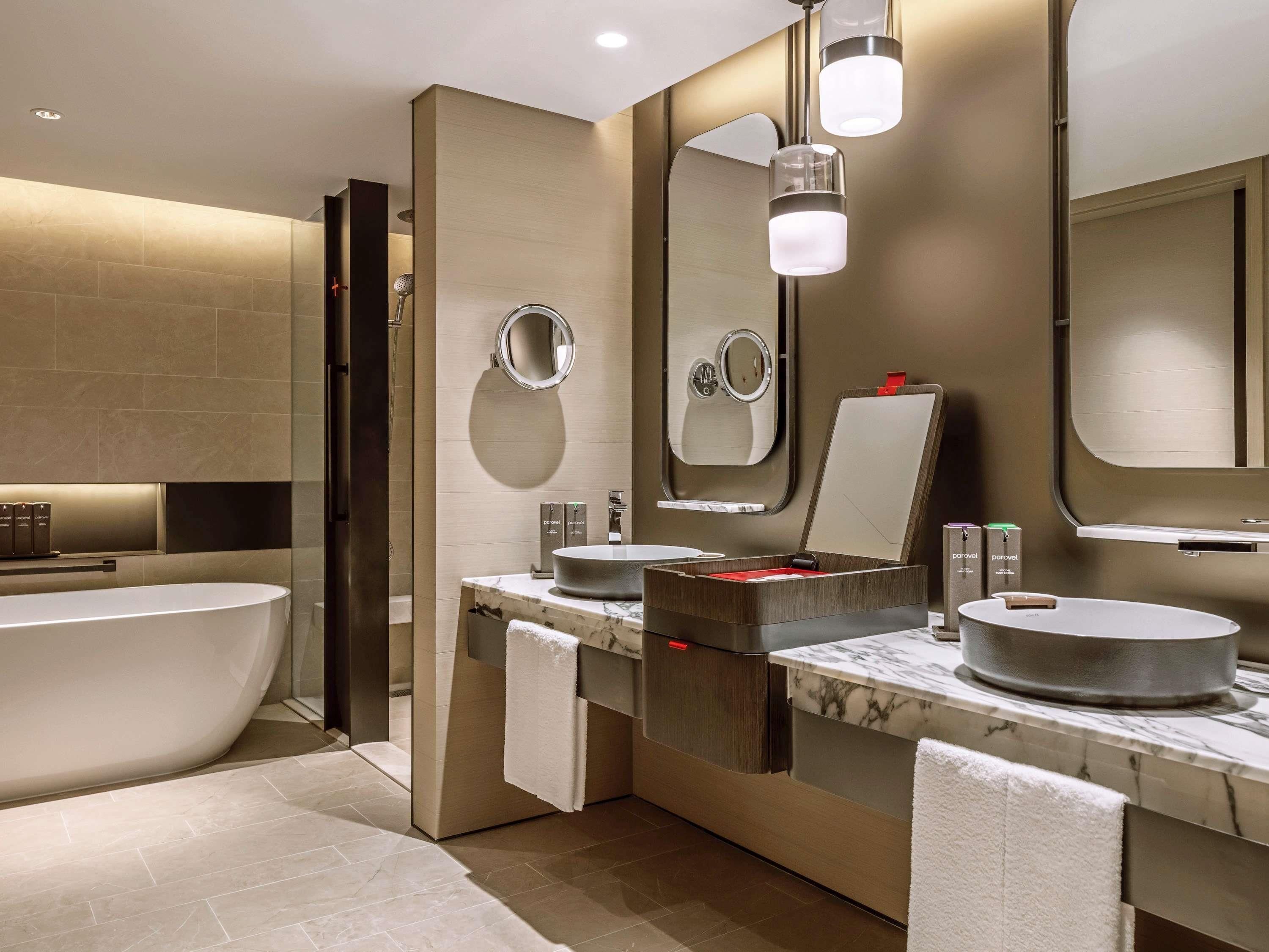 A modern bathroom with a freestanding bathtub, two sinks with round basins, and a large mirror.