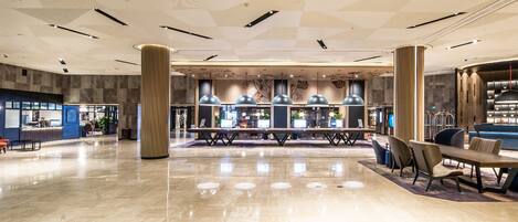 A spacious lobby with a central seating area, a reception desk, and a bar.