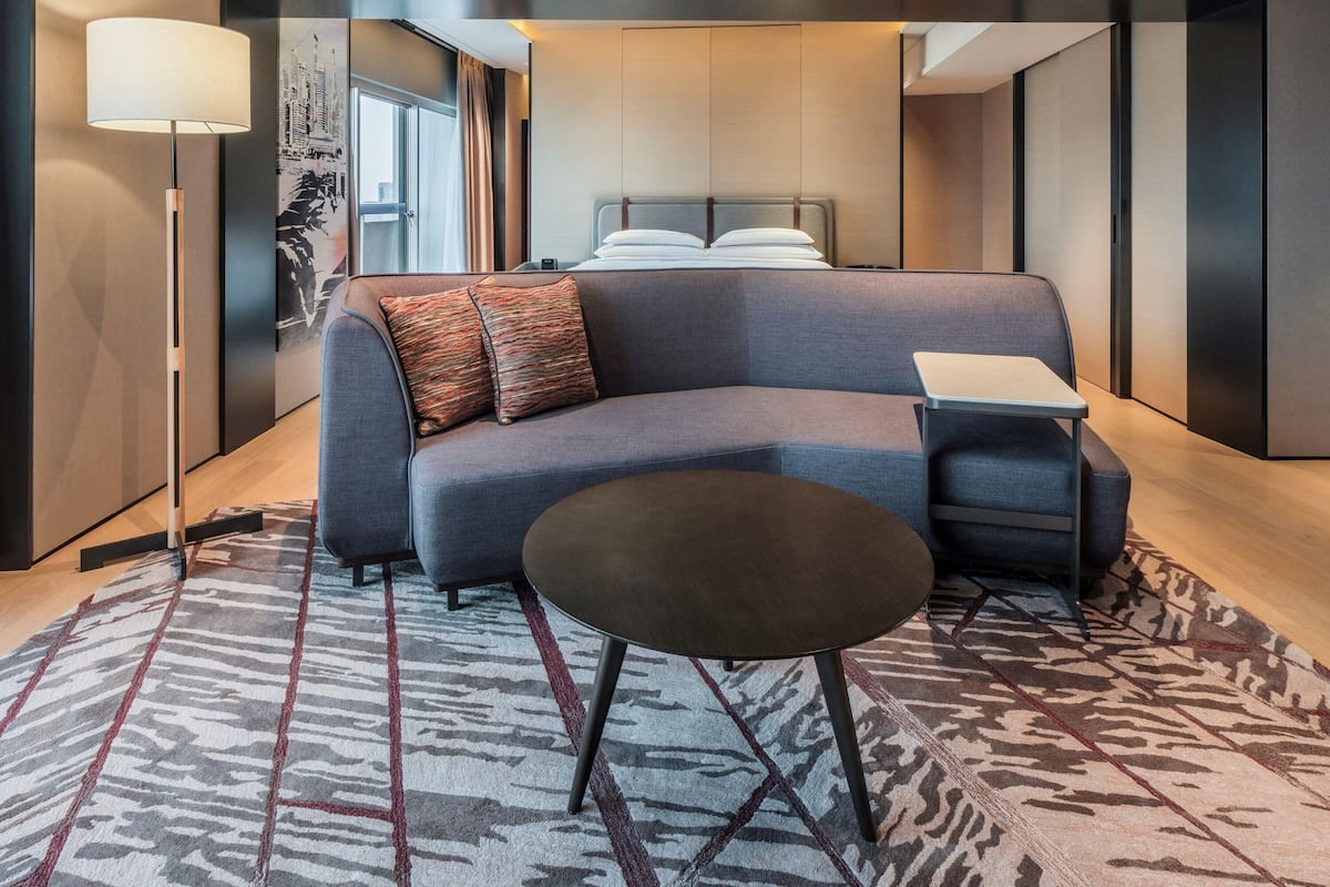 Een moderne hotelkamer met een bank, een klein tafeltje, een lamp en een kamerkleed met dessin.