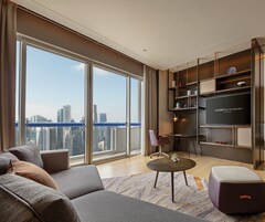 Una sala de estar moderna con un ventanal grande, un sofá, una mesa de centro y un televisor sobre una estantería.