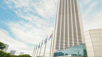 A tall hotel with a modern glass facade and multiple flags in front.
