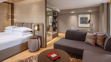 Une chambre d’hôtel moderne, équipée d’un lit, d’un canapé, d’une table basse et d’un miroir.