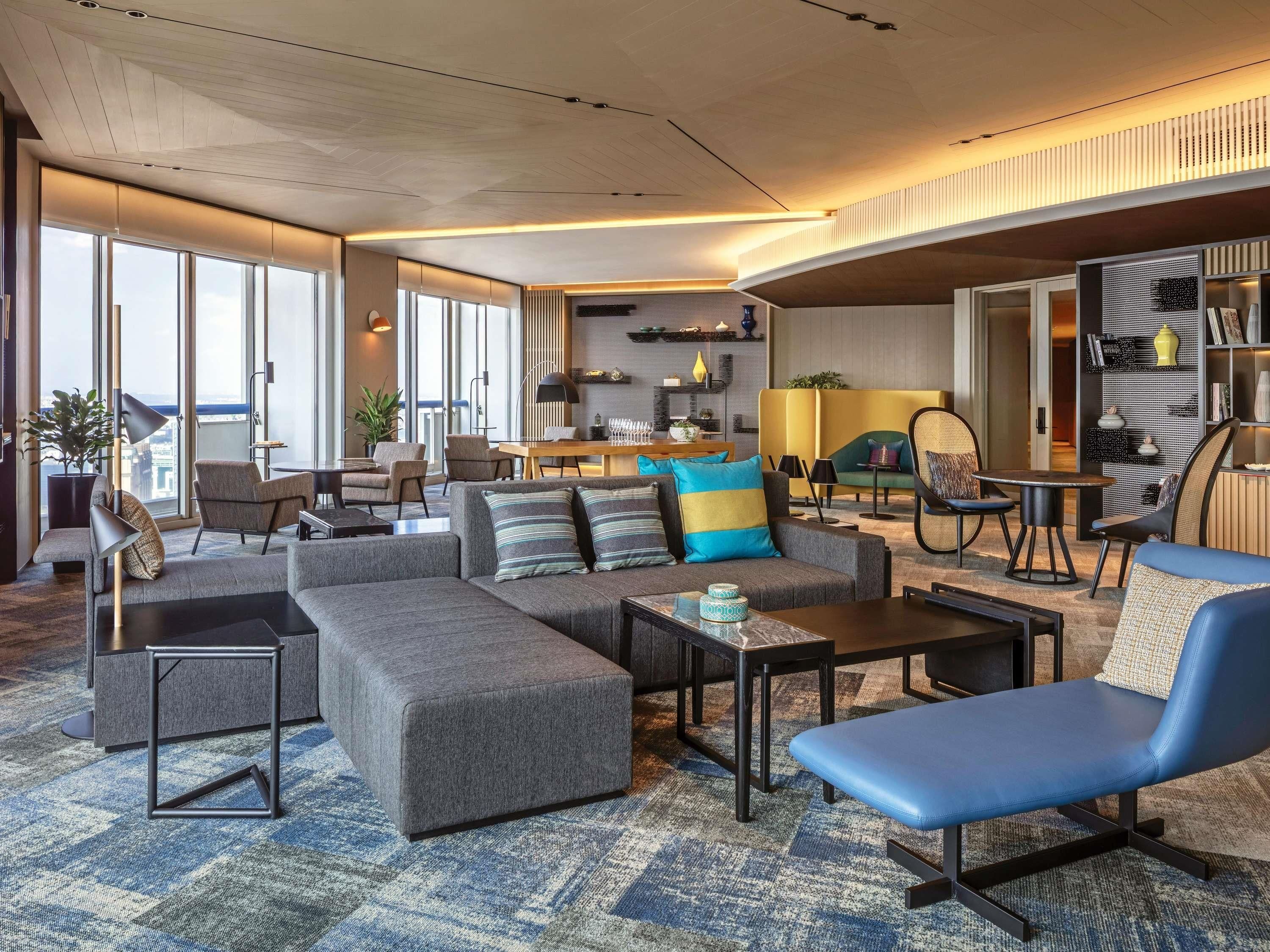 Una sala de estar moderna con un sofá, un sillón y una mesa de centro, un comedor con sillas y una cocina al fondo.