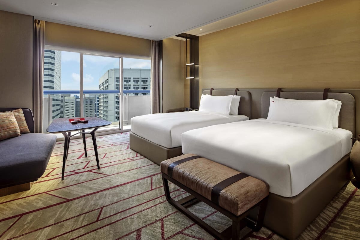 Een hotelkamer met twee bedden, een bank, een tafeltje en uitzicht op de stad.