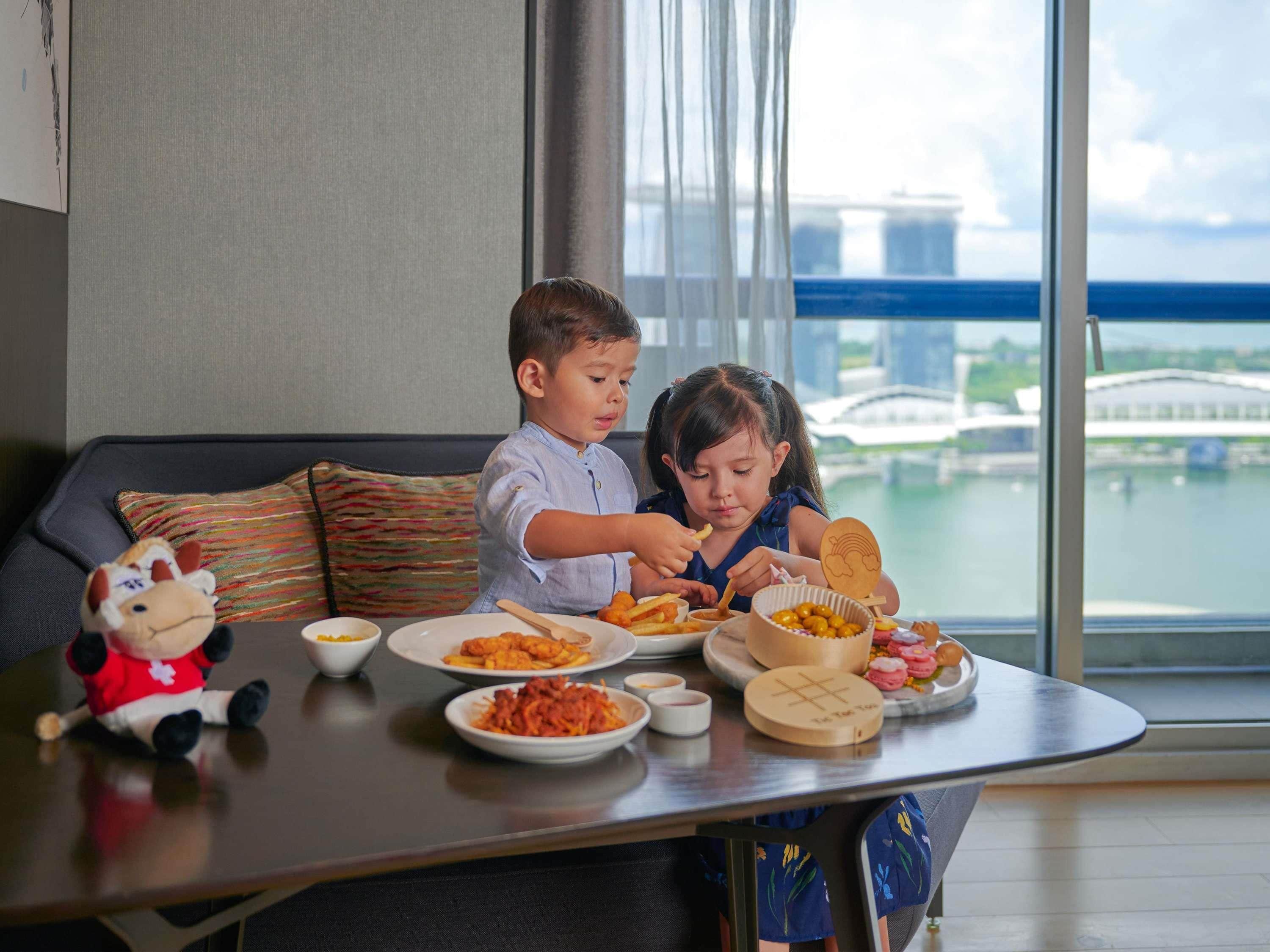 Una mesa de comedor con comida, un sofá y vistas a un puente y al agua.