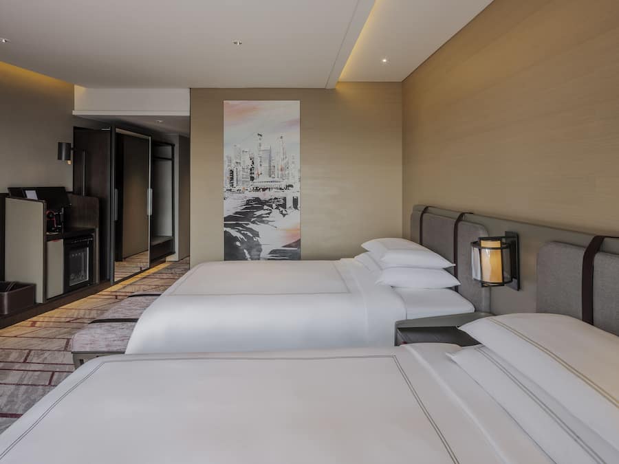 A hotel room with two beds, a large painting on the wall, a desk with a computer, and a lamp.