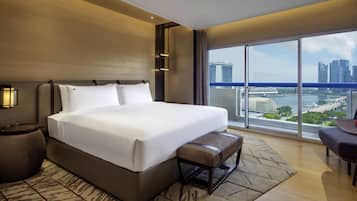 Une chambre d’hôtel moderne avec un grand lit, une banquette, un bureau et une vue sur le paysage urbain.