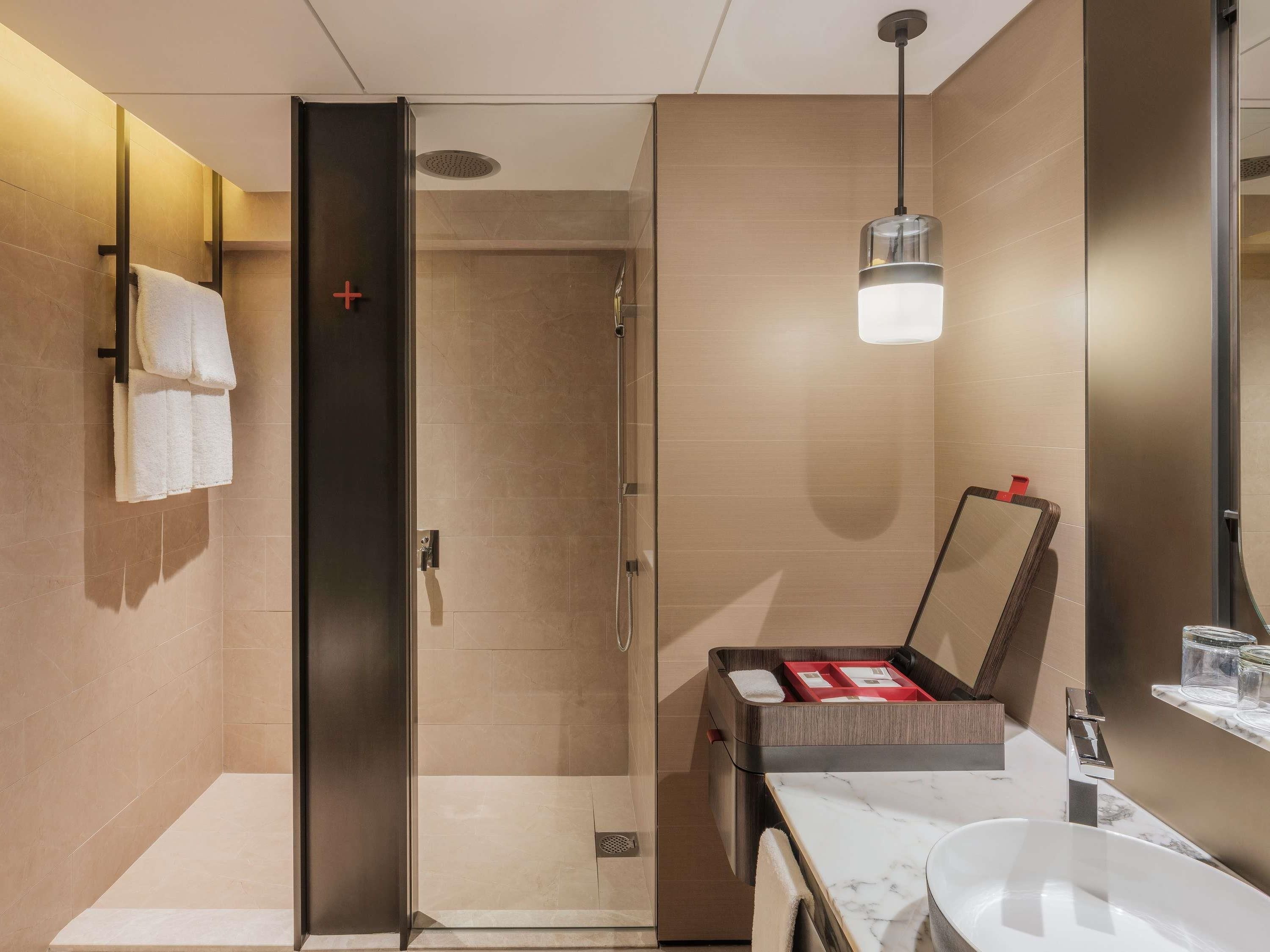 Une salle de bain moderne dotée d’une douche à parois de verre, d’un lavabo en marbre et d’un meuble-vasque intégré.