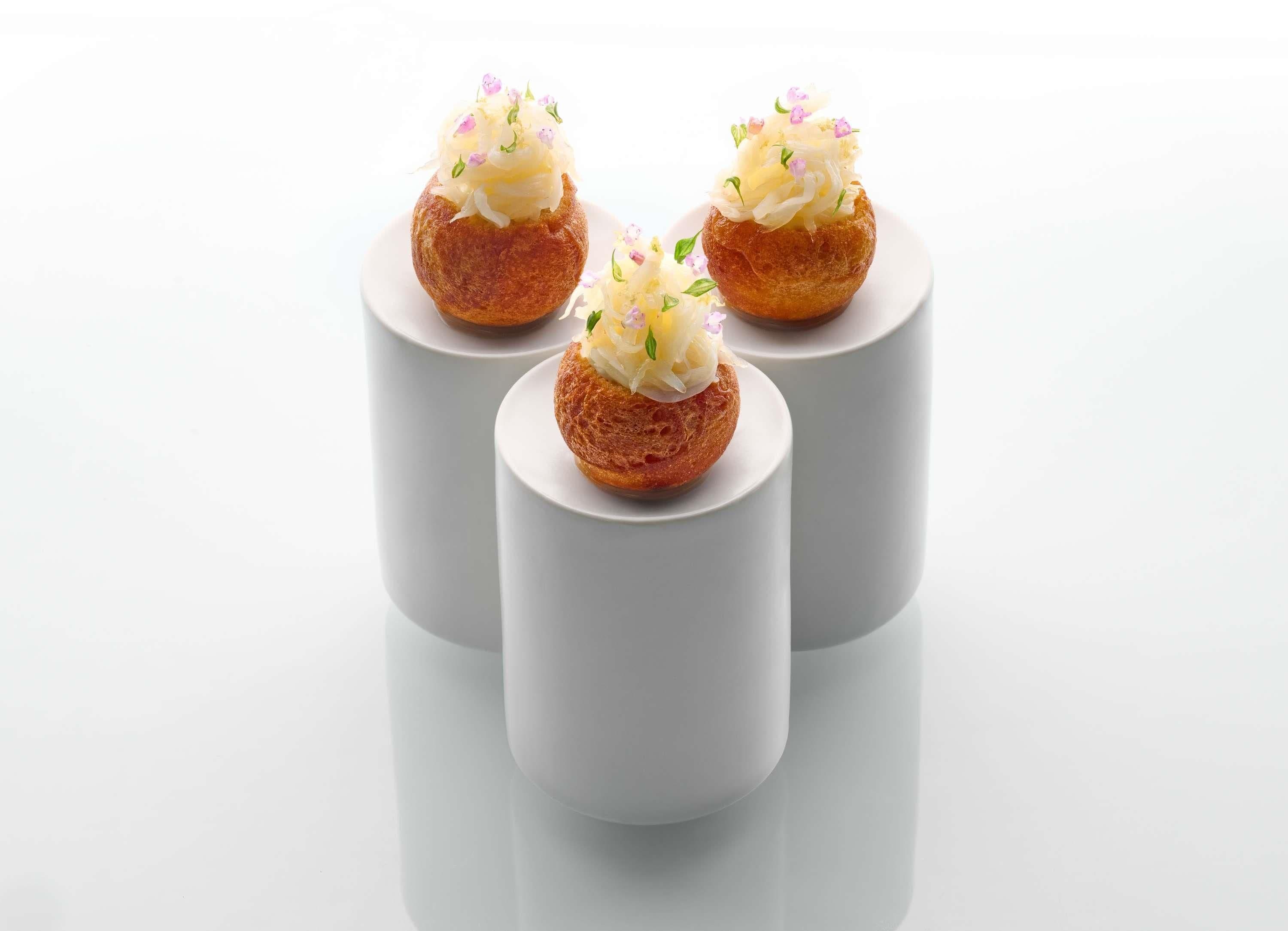 Three pastries on white cylindrical stands.