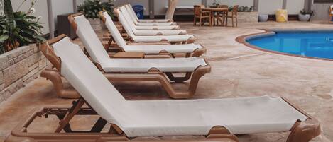 Un espace aménagé au bord de la piscine, avec des chaises longues et une piscine.