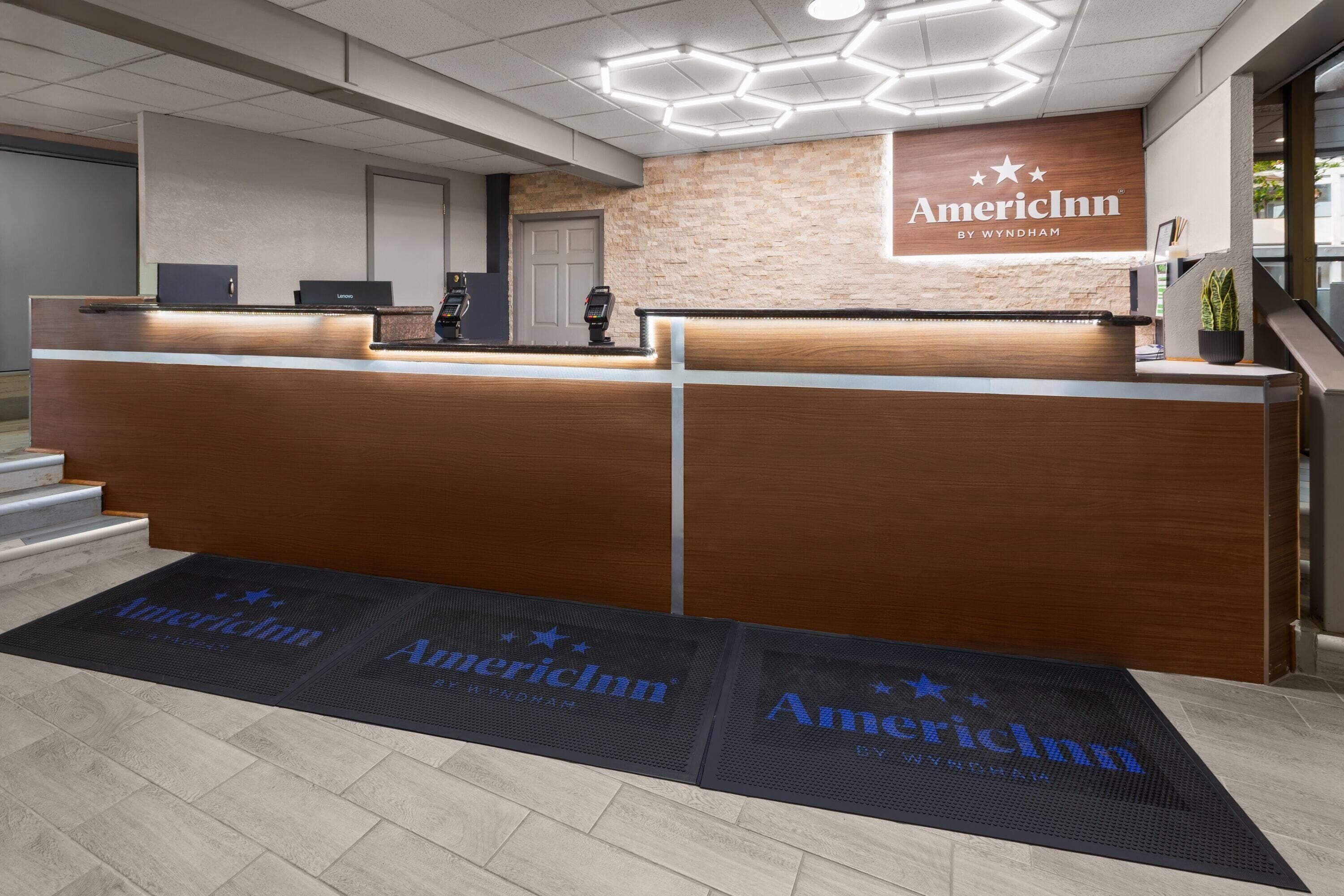 A reception desk with a wooden finish and a sign that reads 'AmericInn by Wyndham'.