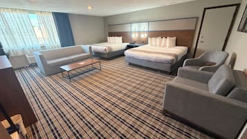 A hotel room with a bed, two sofas, a coffee table, and a desk.