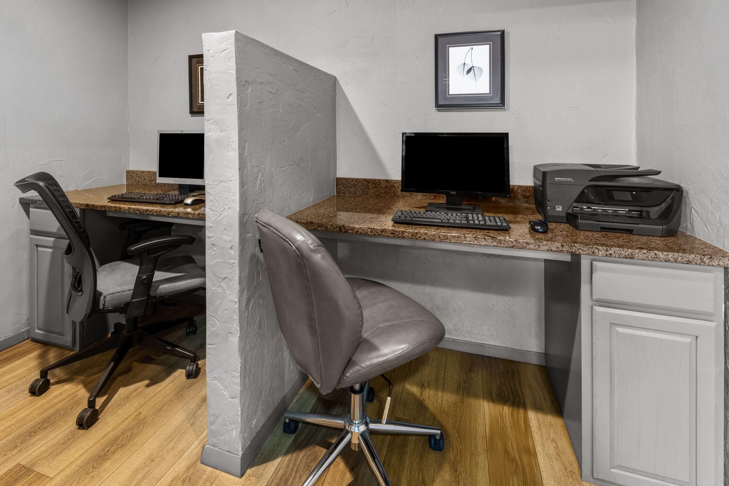 A workspace with two desks, computers, chairs, and a printer.