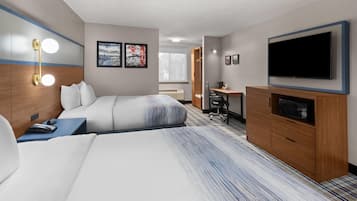 Een hotelkamer met twee bedden, een bureau, een televisie en kunstwerken aan de wanden.