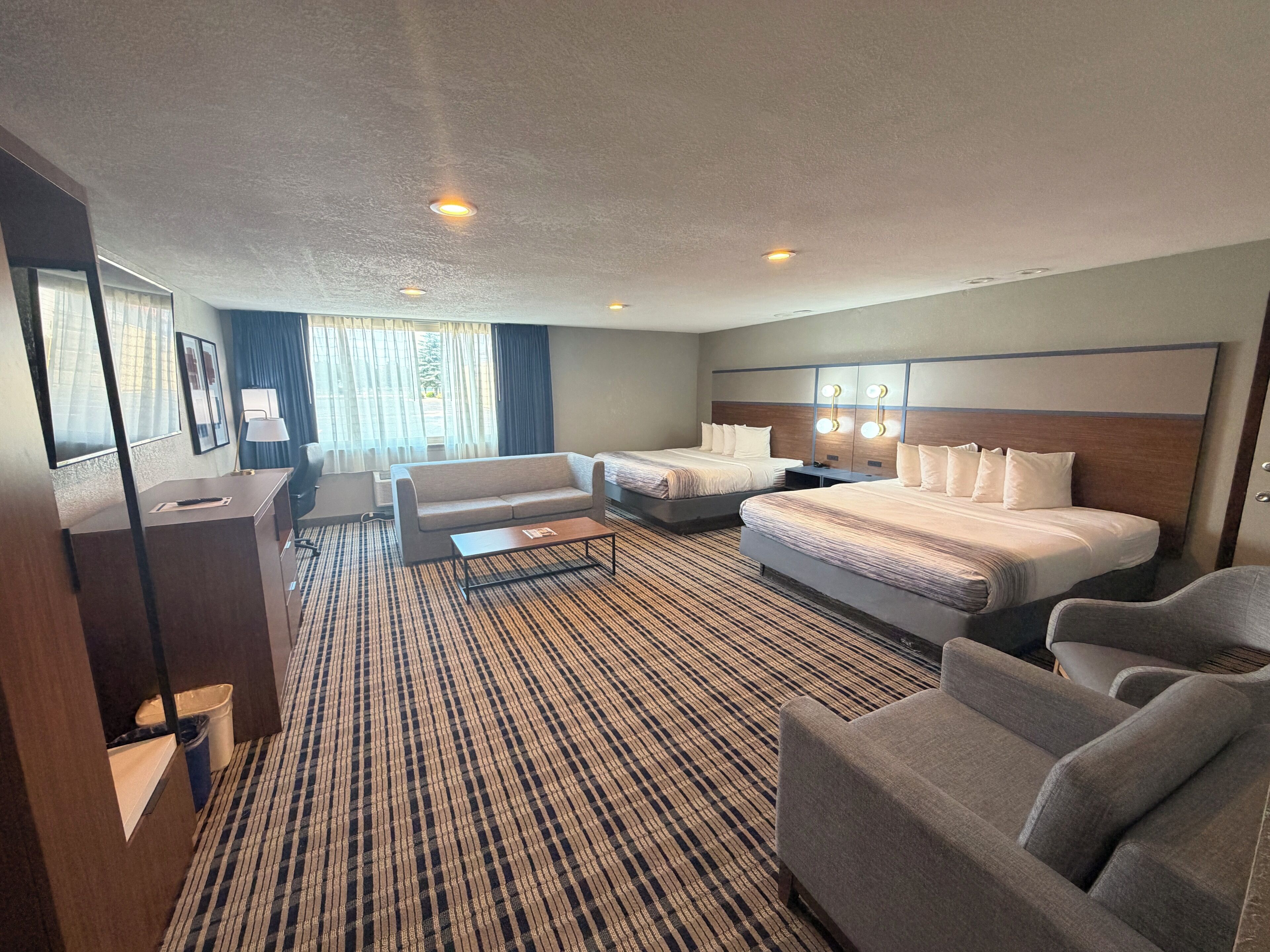 Habitación de hotel con dos camas, un sofá, un escritorio y vistas al exterior.