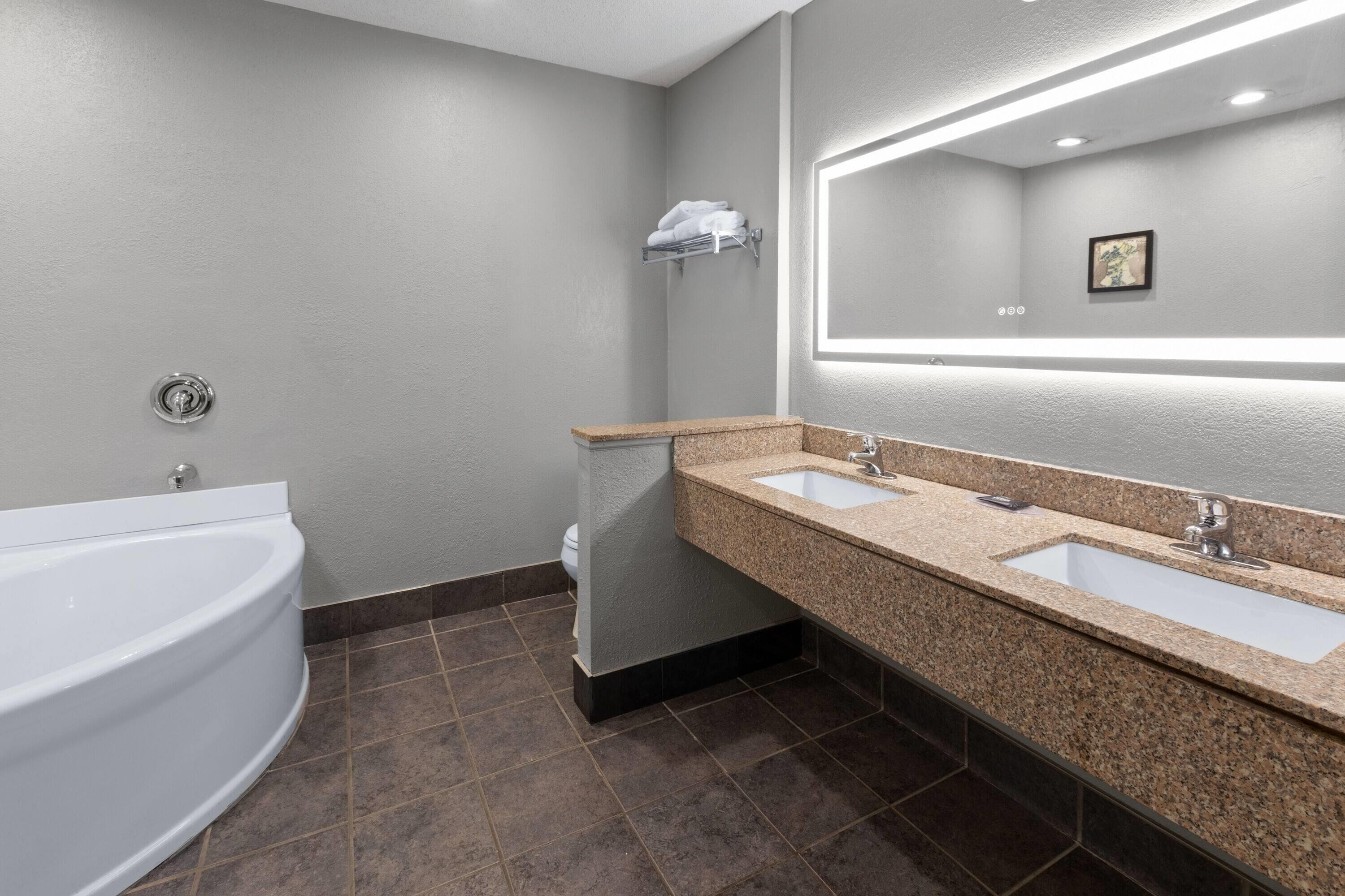 Un baño moderno con una bañera independiente, un tocador doble y un perchero de pared.