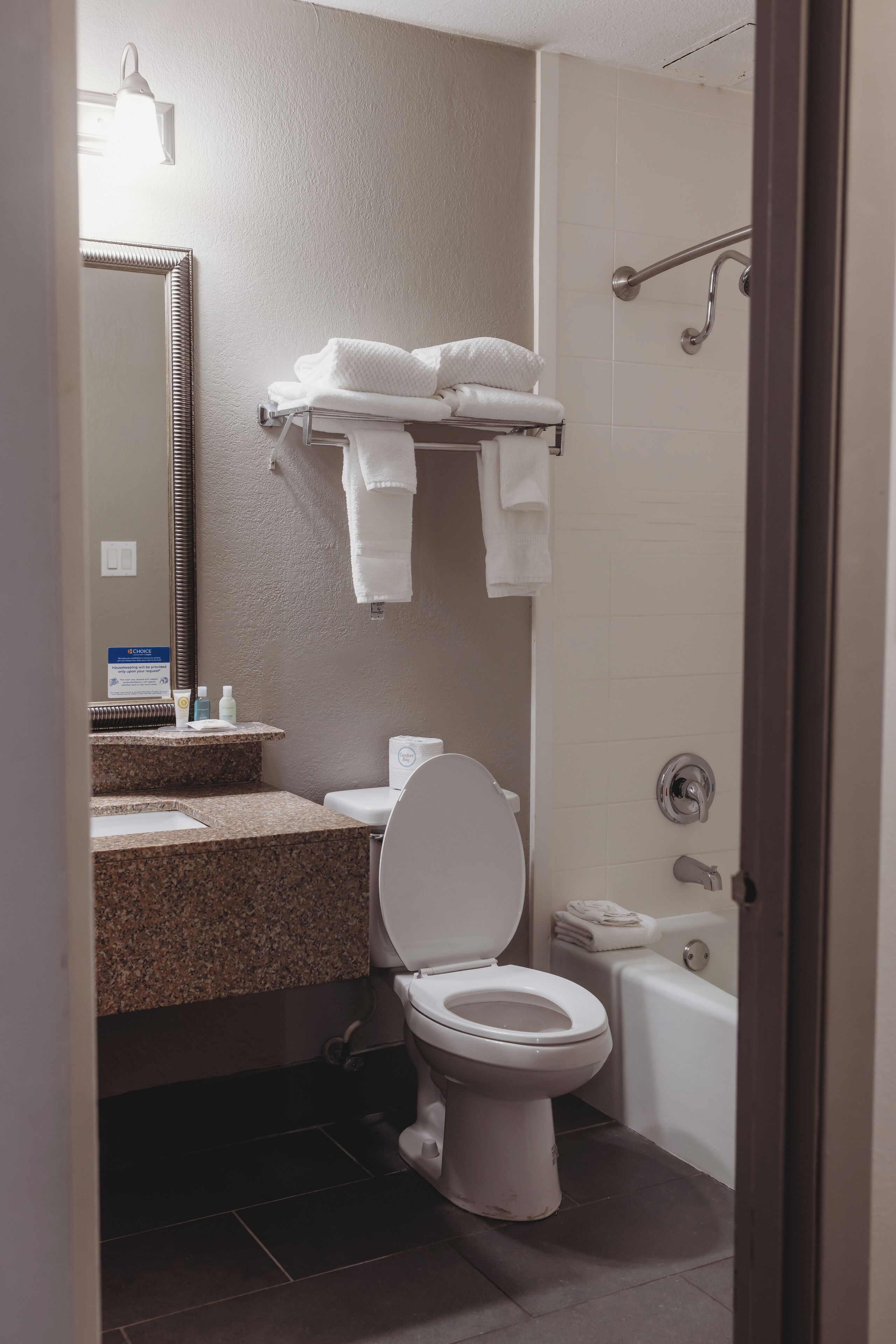 A bathroom with a toilet, sink, mirror, towel rack, and shower.
