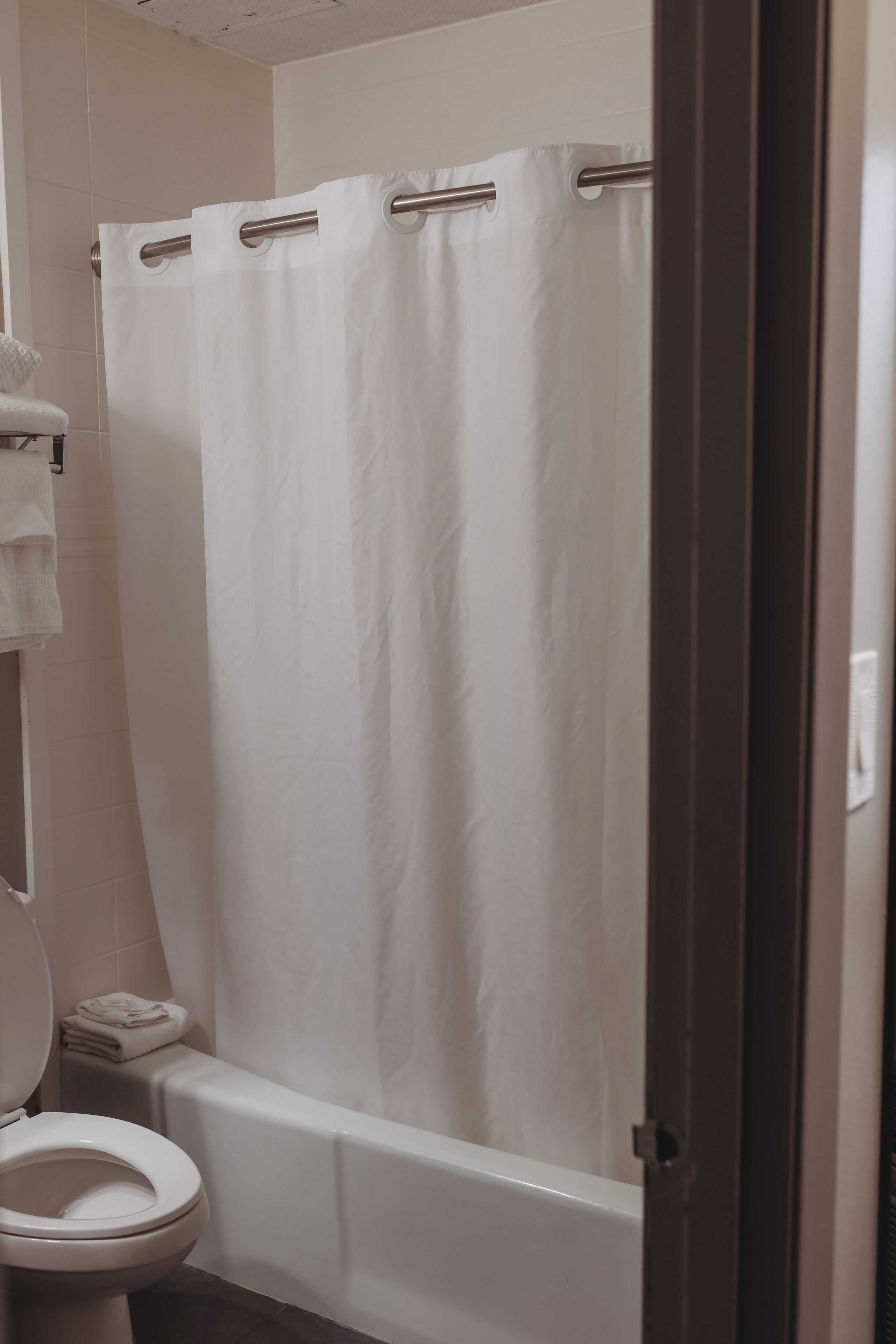 Ein Badezimmer mit Toilette, Badewanne und weißem Duschvorhang, alles in Weiß.