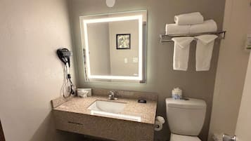 Un baño con lavabo, espejo, inodoro y toallero.