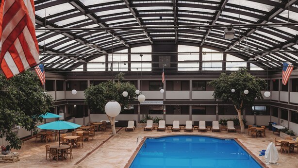 Un área de piscina interior con dos piscinas, sillas de descanso y banderas estadounidenses.